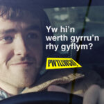 A man driving with the text "Yw hi'n werth gyrru'n rhy gyflym?"